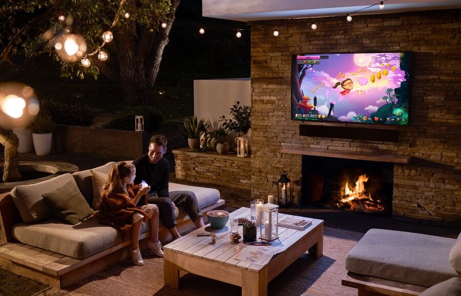 A well-lit patio at night featuring an outdoor TV.
