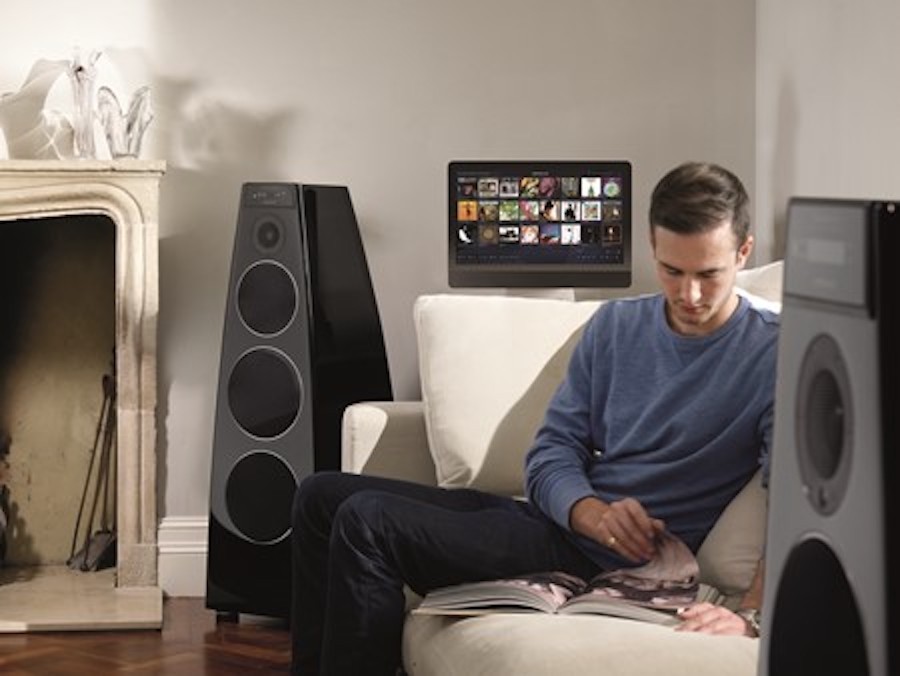 A man sitting on a couch between two Meridian loudspeakers.