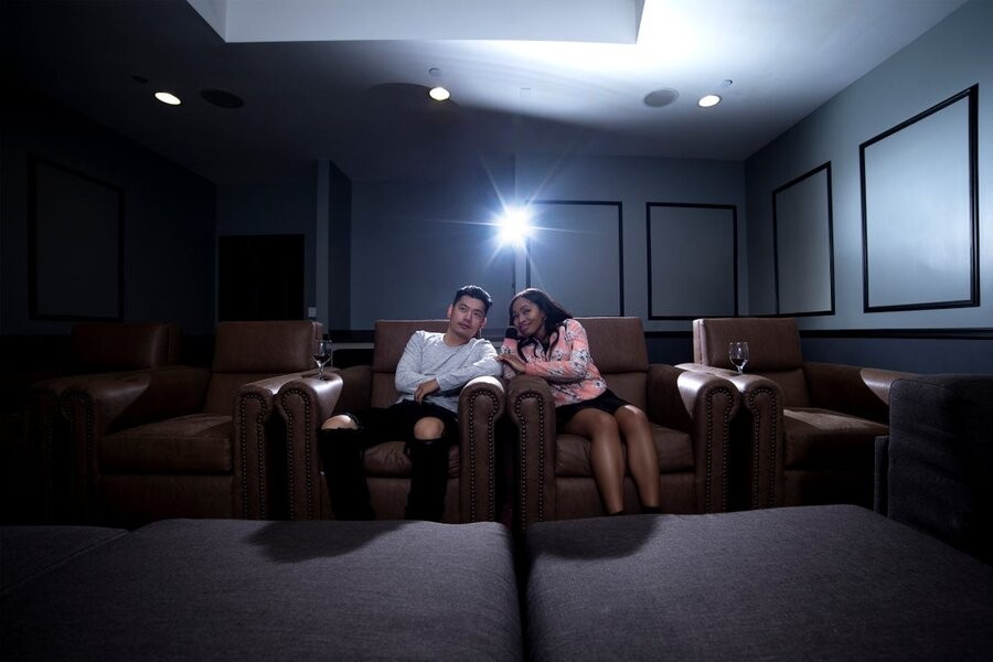 A couple sits and watches the screen in their home cinema featuring top-notch home theater system solutions.