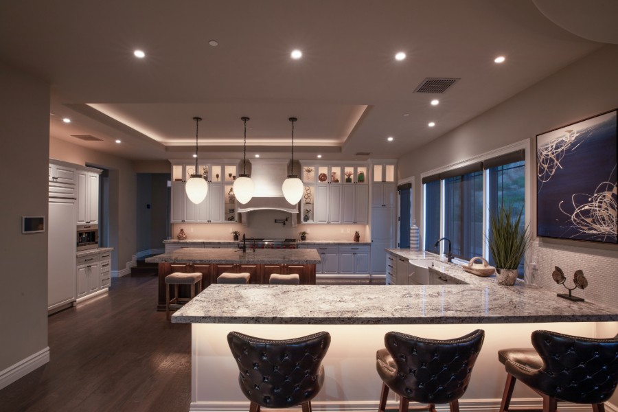 A modern kitchen featuring a center island with bar stools, illuminated by LED lighting